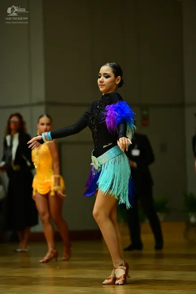 Dancesport competitor: Main female dancer: black long-sleeved latin dress with vibrant blue, purple, an