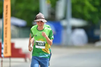 Marathon runner #5283: Runner 1: green and yellow patterned jersey, blue pants, brown patterned bucket 