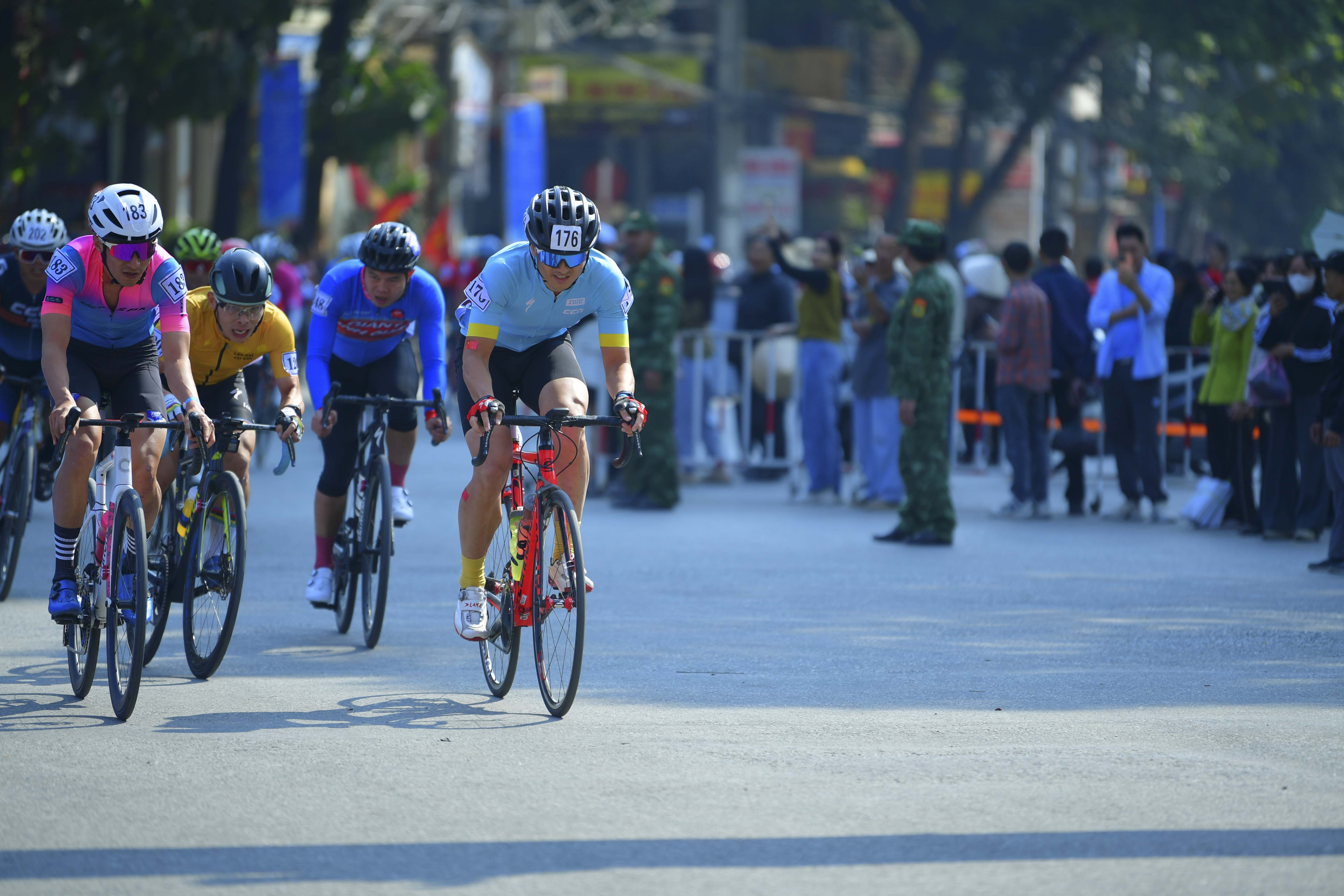 Cyclist: Here's a breakdown of the cyclists' outfits in the photo:

*   **Cyclist 1 (176)