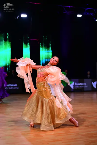 Dancesport competitor: Female dancer: Gold sequined ballroom gown with large, voluminous, peach-colored