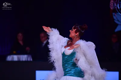 Dancesport competitor: Female dancer: teal satin bodice with white lace/sequin detailing, a large white