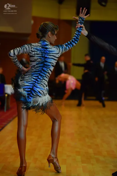 Dancesport competitor: Female dancer in foreground: Latin-style dress with a black, white, and blue tig
