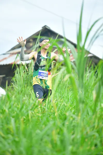 Marathon runner #3905: Runner 1: green and black patterned jersey, black shorts with a white '6', grey 