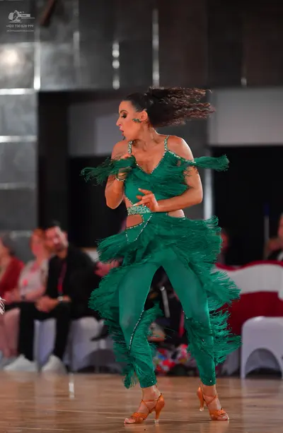 Dancesport competitor: Female dancer: emerald green Latin dance costume with extensive fringe on the to