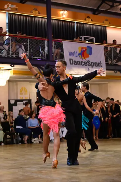 Dancesport competitor: Main female dancer: black long-sleeved top and pink fringe skirt