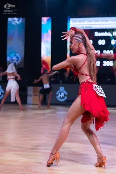 Dancesport competitor: Female dancer in foreground: red latin dress with fringe and red earrings