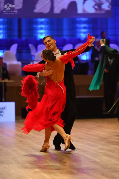 Dancesport competitor: Female dancer: red latin dress with long sleeves and embellishments