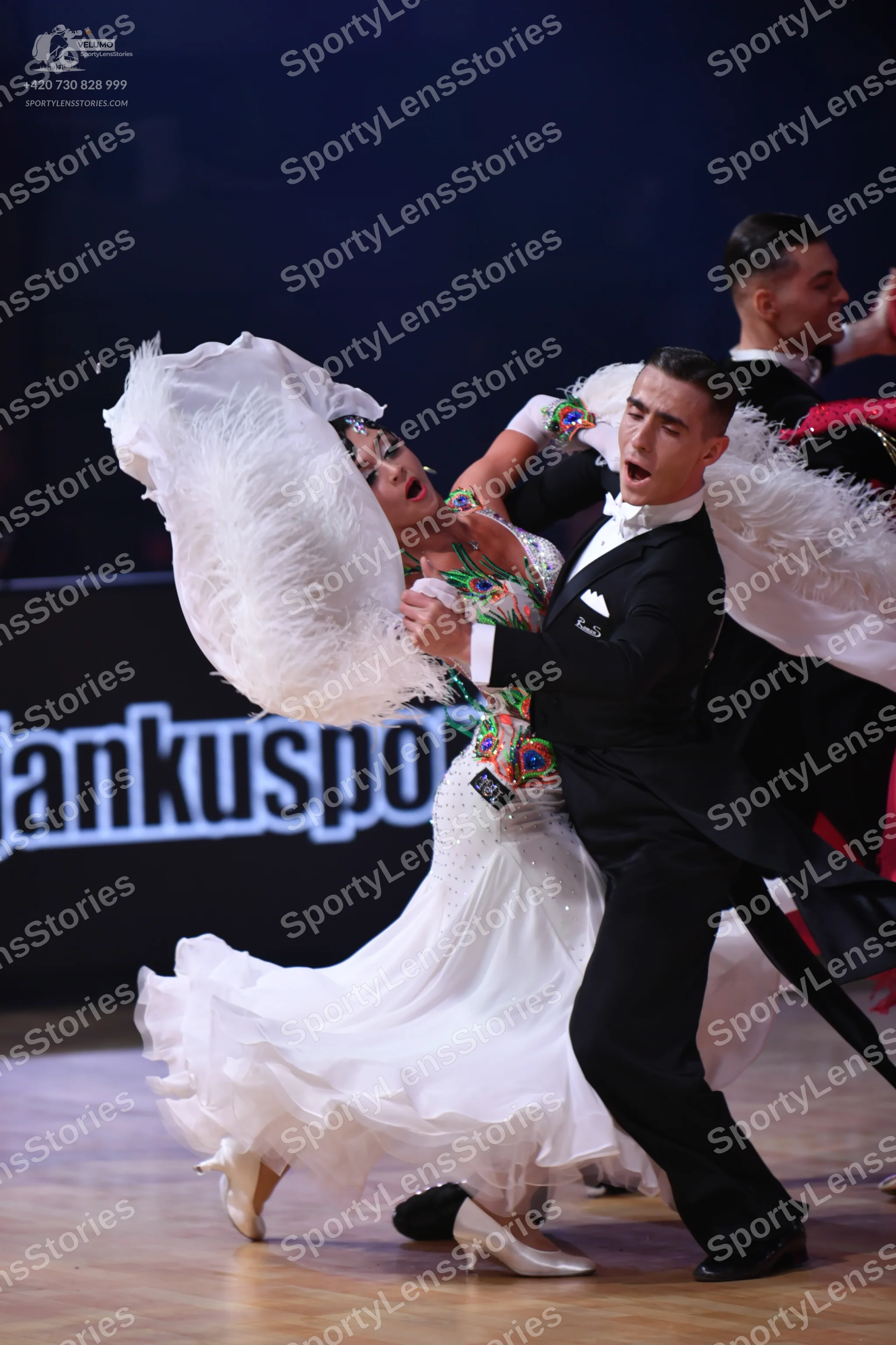 Dancesport competitor: Female dancer: white ballroom gown with a large, voluminous ruffled skirt, a col