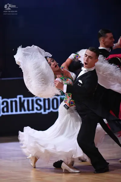 Dancesport competitor: Female dancer: white ballroom gown with a large, voluminous ruffled skirt, a col