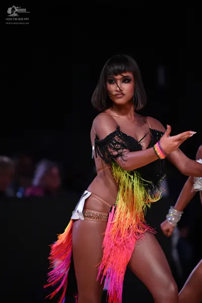 Dancesport competitor: Female dancer: black latin dance costume with a black fringed top and long, mult