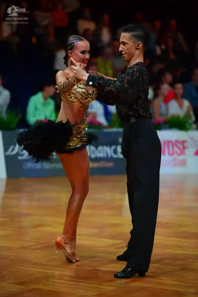 Dancesport competitor: Female dancer: gold and black latin dress with a sequined top and a black ruffle
