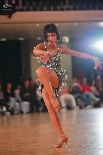 Dancesport competitor: Female dancer: dark grey or black Latin dress covered in silver sequins and rhin