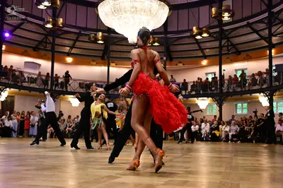 Dancesport competitor: Female dancer in foreground: red latin dress with ruffled or fringed layers