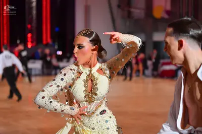Dancesport competitor: Female dancer: cream-colored long-sleeve latin dress featuring large silver sequ