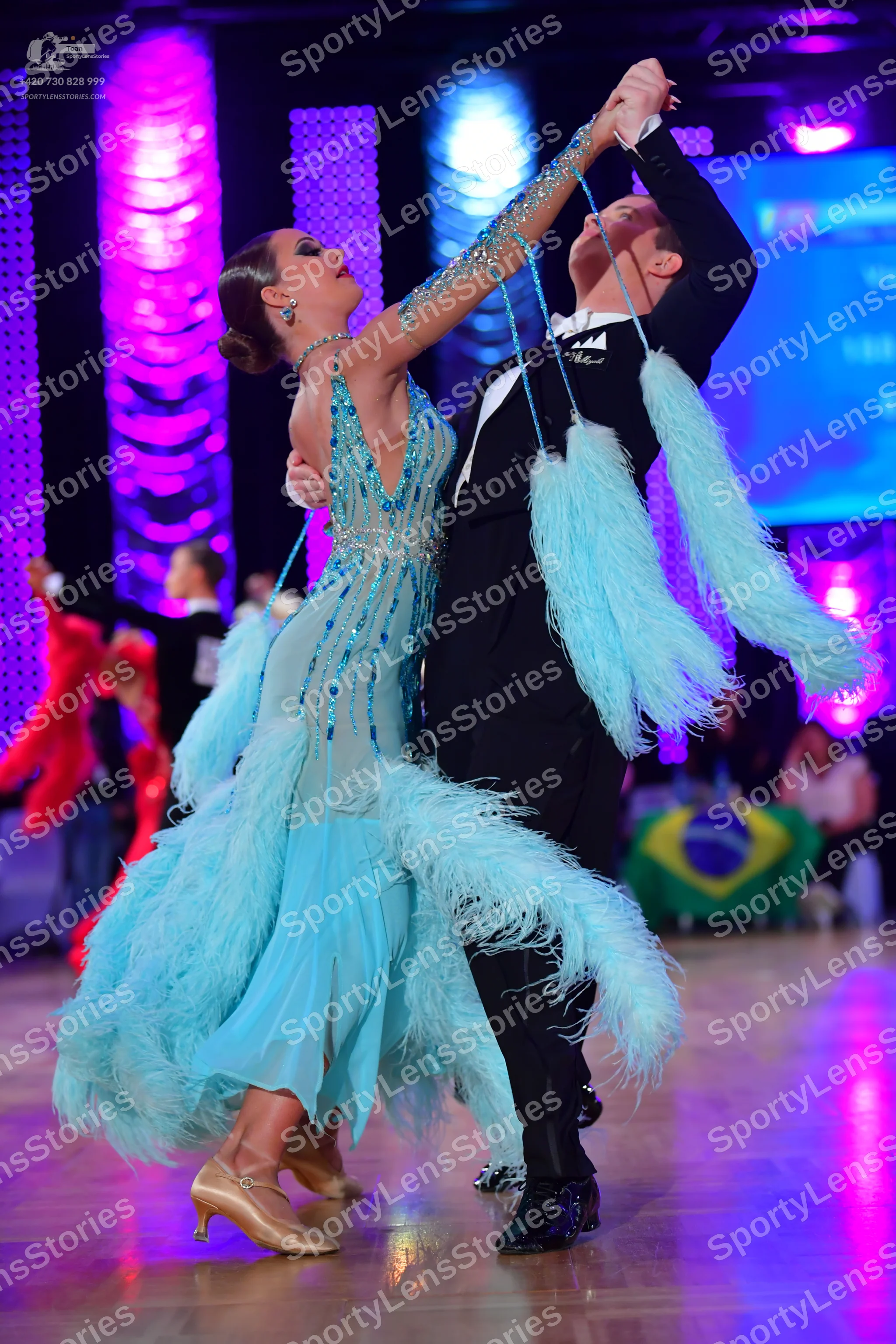 Dancesport competitor: Female dancer: light blue latin dress with sequins and large feather-like fringe