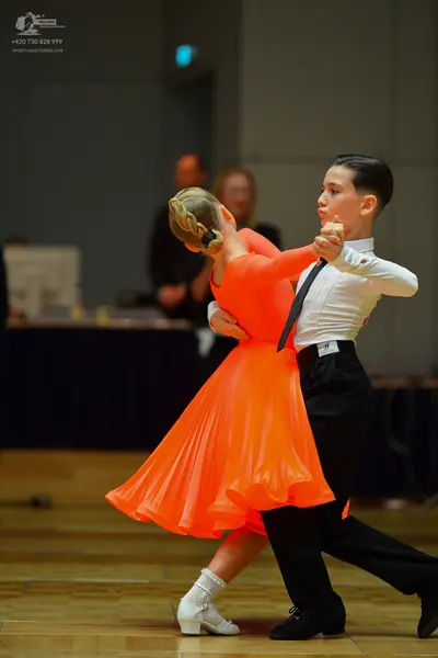 Dancesport competitor: Female dancer: bright orange flowing dress with a full skirt