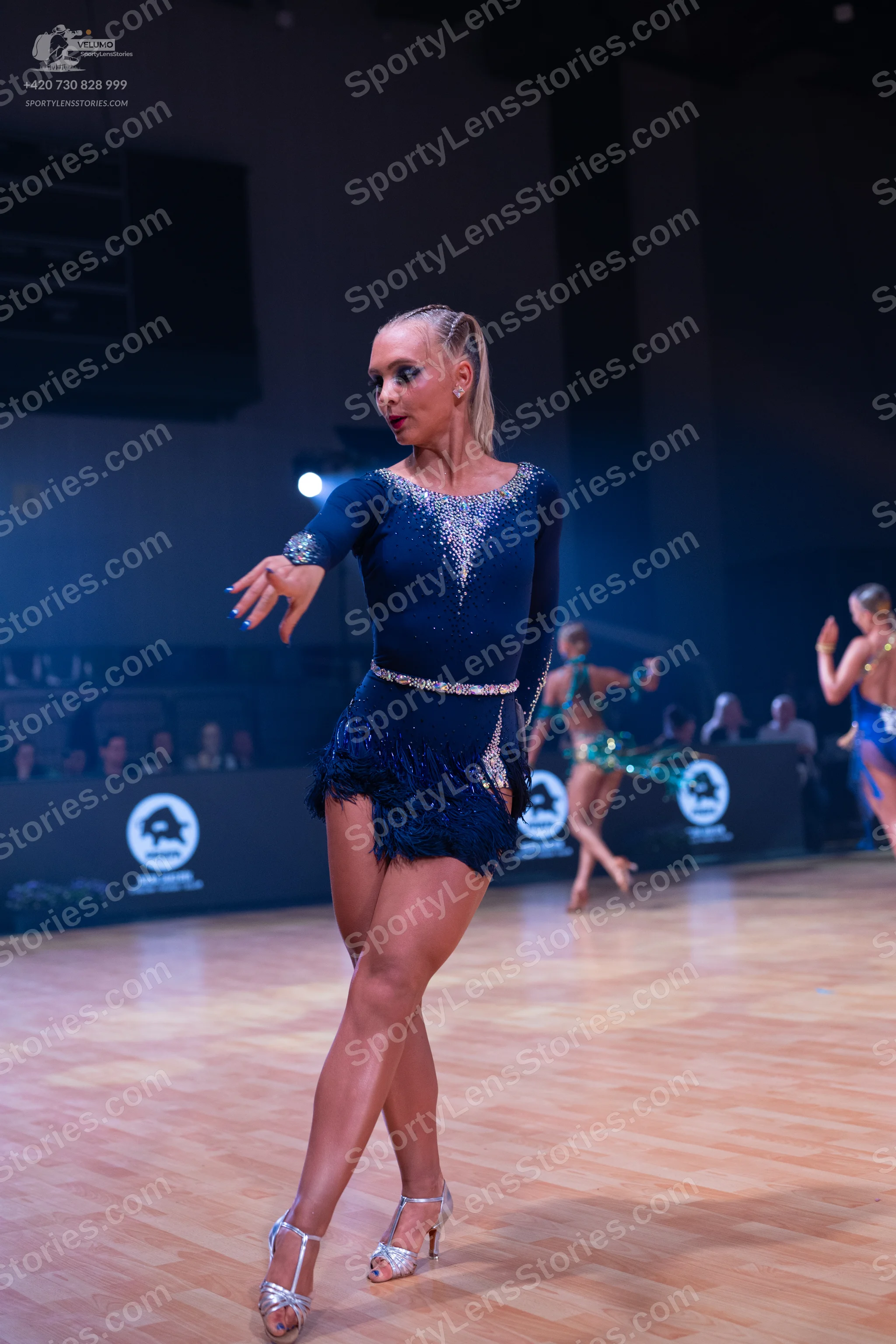 Dancesport competitor: Female dancer (foreground): navy blue latin dress with sequins and fringe