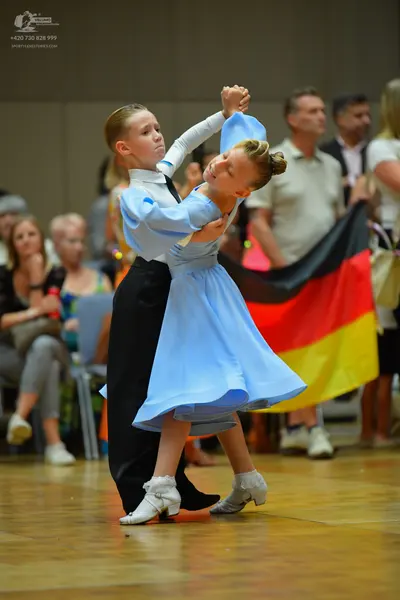 Dancesport competitor: Male dancer: white long-sleeved shirt with a black tie, black trousers, and whit