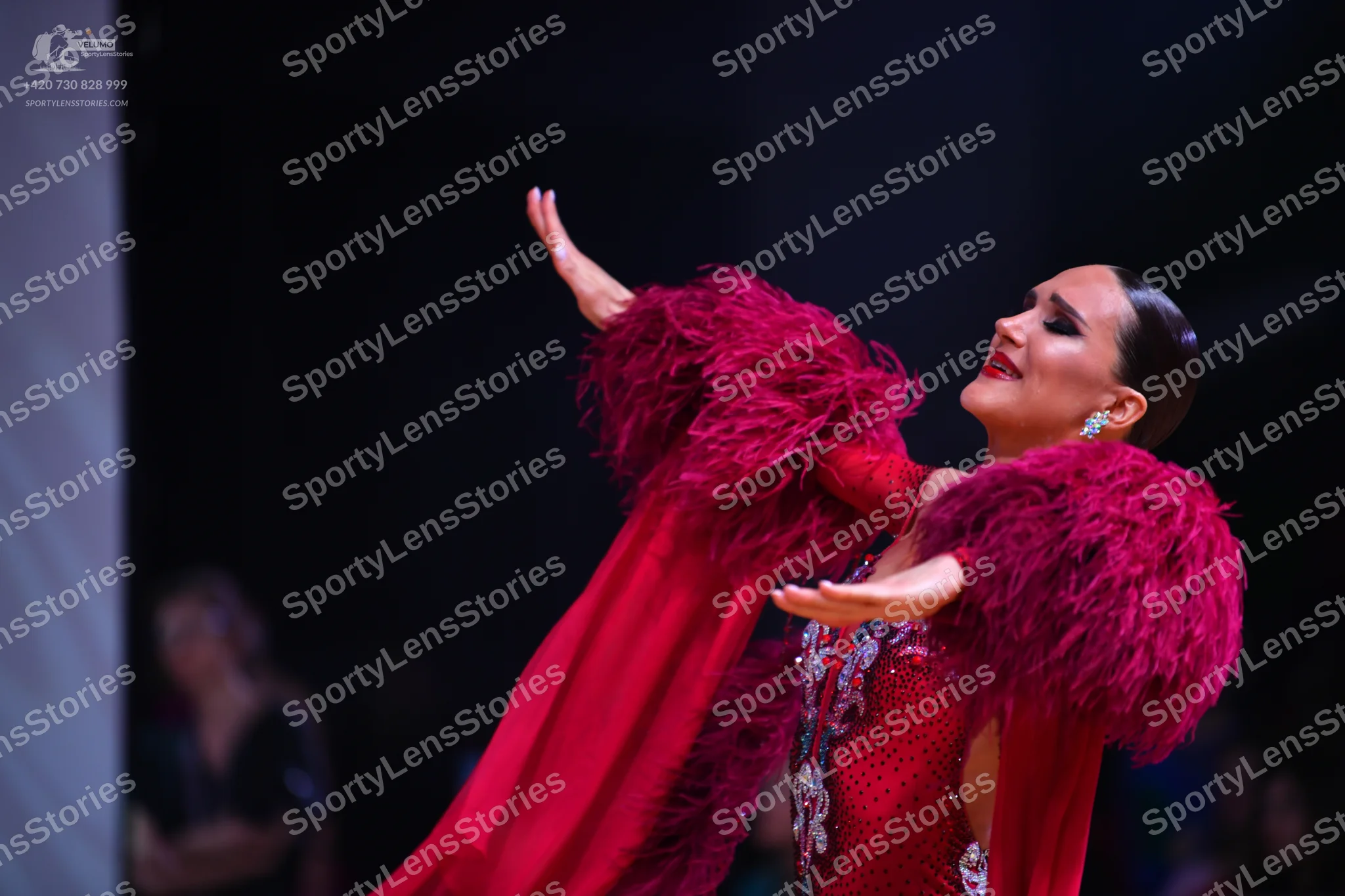 Dancesport competitor: Female dancer: red Latin dress with large, voluminous red feather/fringe details