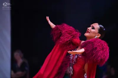 Dancesport competitor: Female dancer: red Latin dress with large, voluminous red feather/fringe details