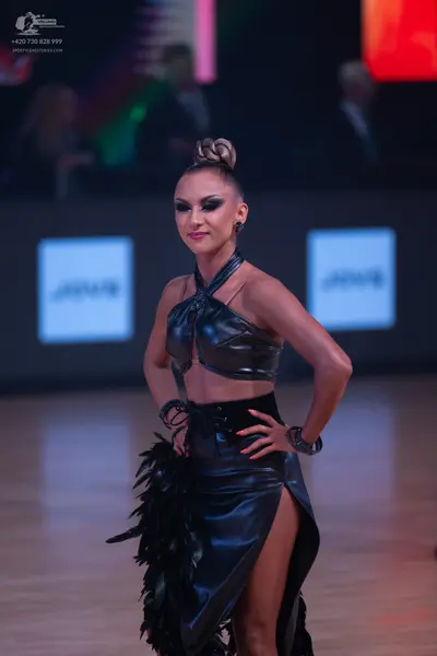 Dancesport competitor: Female dancer: black two-piece latin costume made of shiny, leather-like fabric,