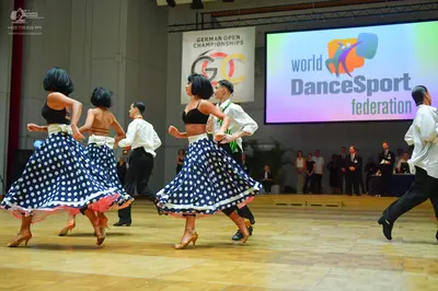 Dancesport competitor: Female dancers: black crop tops with wide white waistbands, and blue skirts with