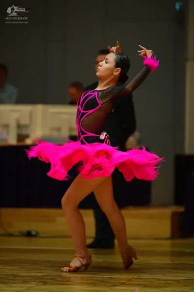 Dancesport competitor: Female dancer: black and bright pink latin dress with a large, voluminous pink f