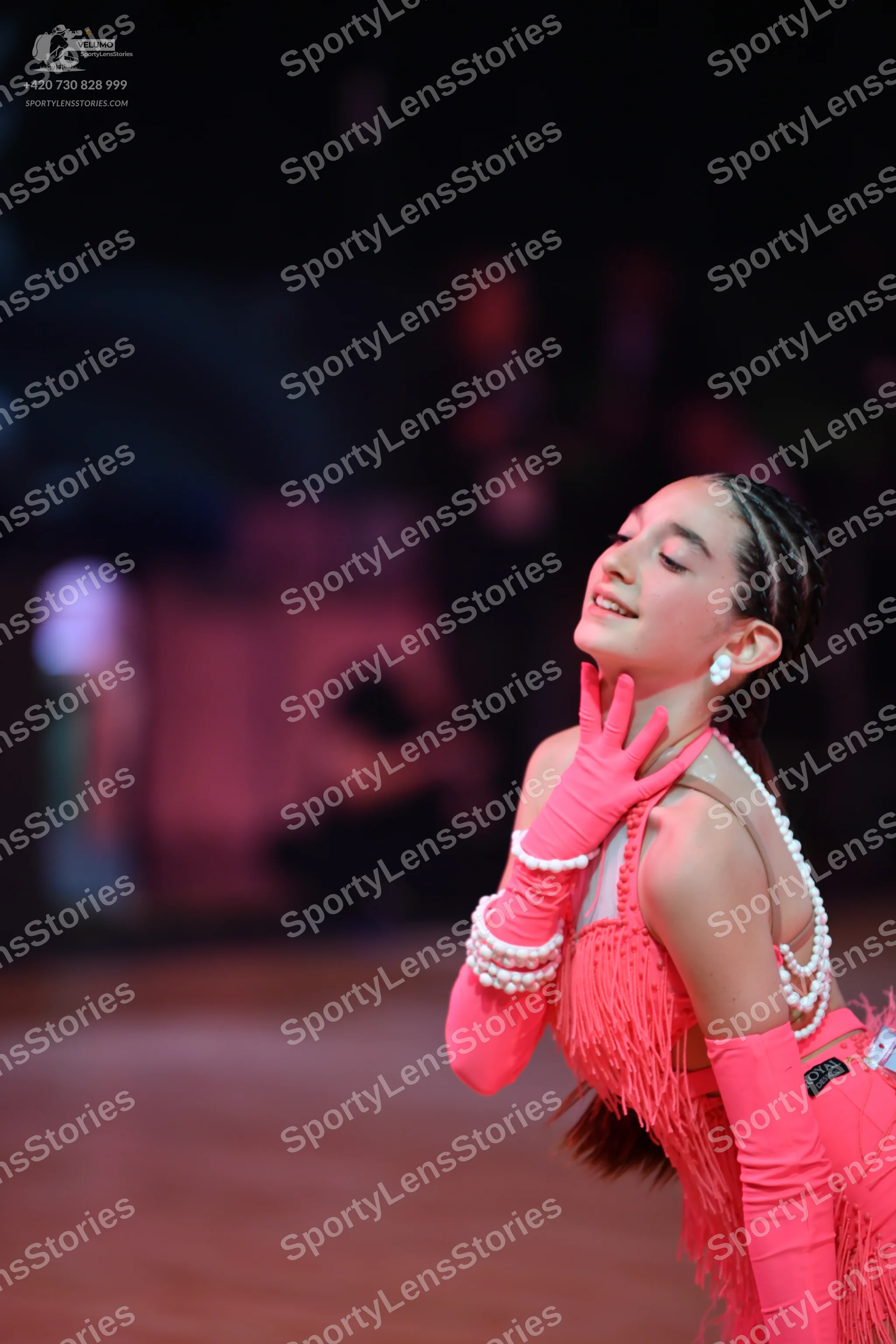 Dancesport competitor: Female dancer: coral pink Latin dance costume with fringe, long matching gloves,