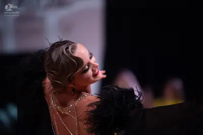 Dancesport competitor: Female dancer: black dress with sparkly/sequined details and large black feather