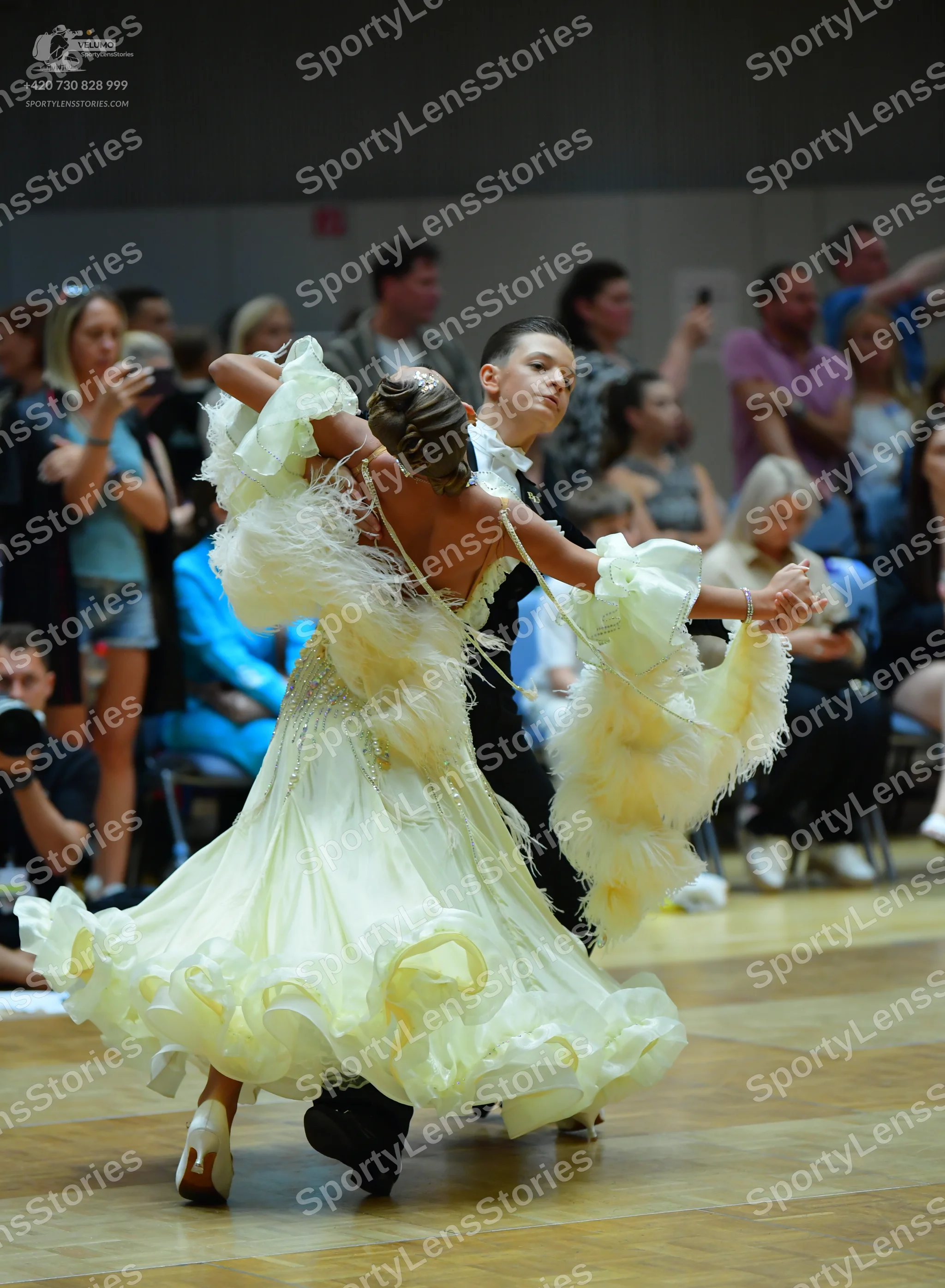 Dancesport competitor: Female dancer: voluminous, pale yellow ballgown with layered, ruffled fabric and