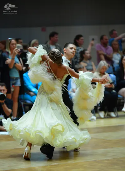 Dancesport competitor: Female dancer: voluminous, pale yellow ballgown with layered, ruffled fabric and