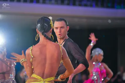Dancesport competitor: Female dancer (foreground): yellow/gold Latin-style costume with thin straps and