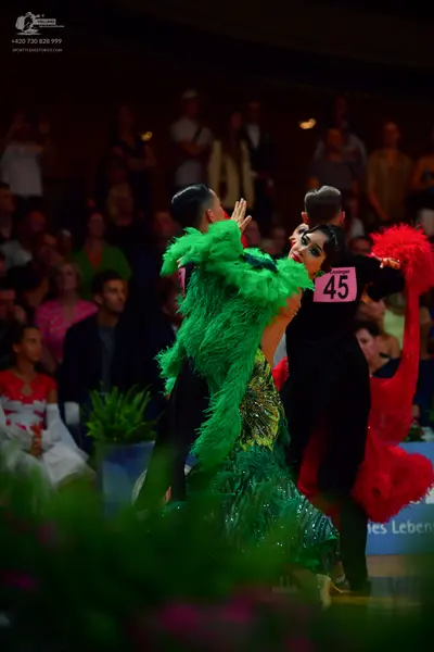 Dancesport competitor: Female dancer 1: vibrant green ballroom dress with dense, textured fringe or fea