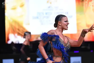 Dancesport competitor: Primary female dancer: blue latin dress with blue fringe and rhinestone embellis