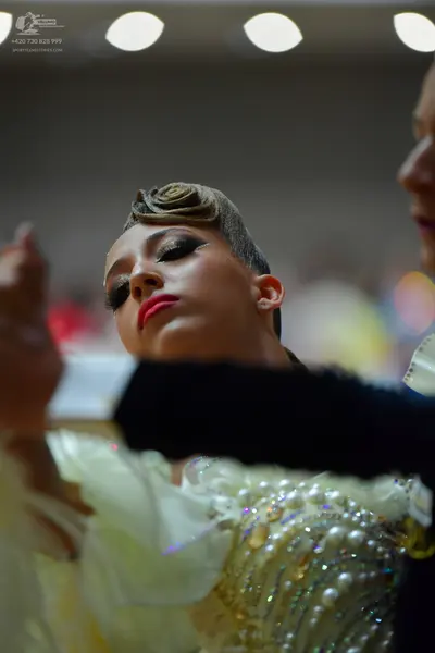 Dancesport competitor: Female dancer: Cream-colored ballroom gown featuring extensive embellishments of