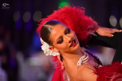Dancesport competitor: Female dancer: red Latin dance costume with large red feathers, a pearl necklace