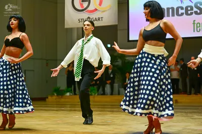 Dancesport competitor: Female dancers: black bra-style crop tops and long, navy blue skirts with large 