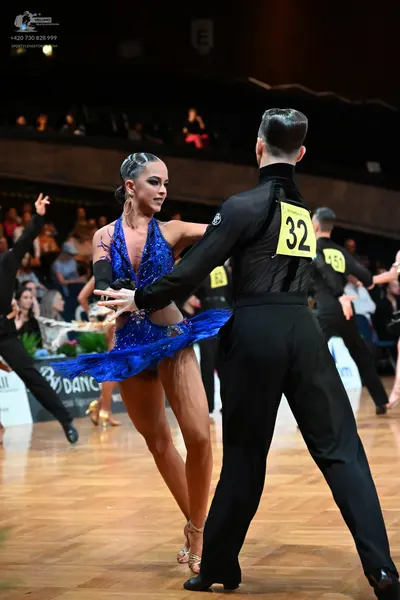 Dancesport competitor #32, #59: Male dancer (foreground): black long-sleeved shirt and black trousers