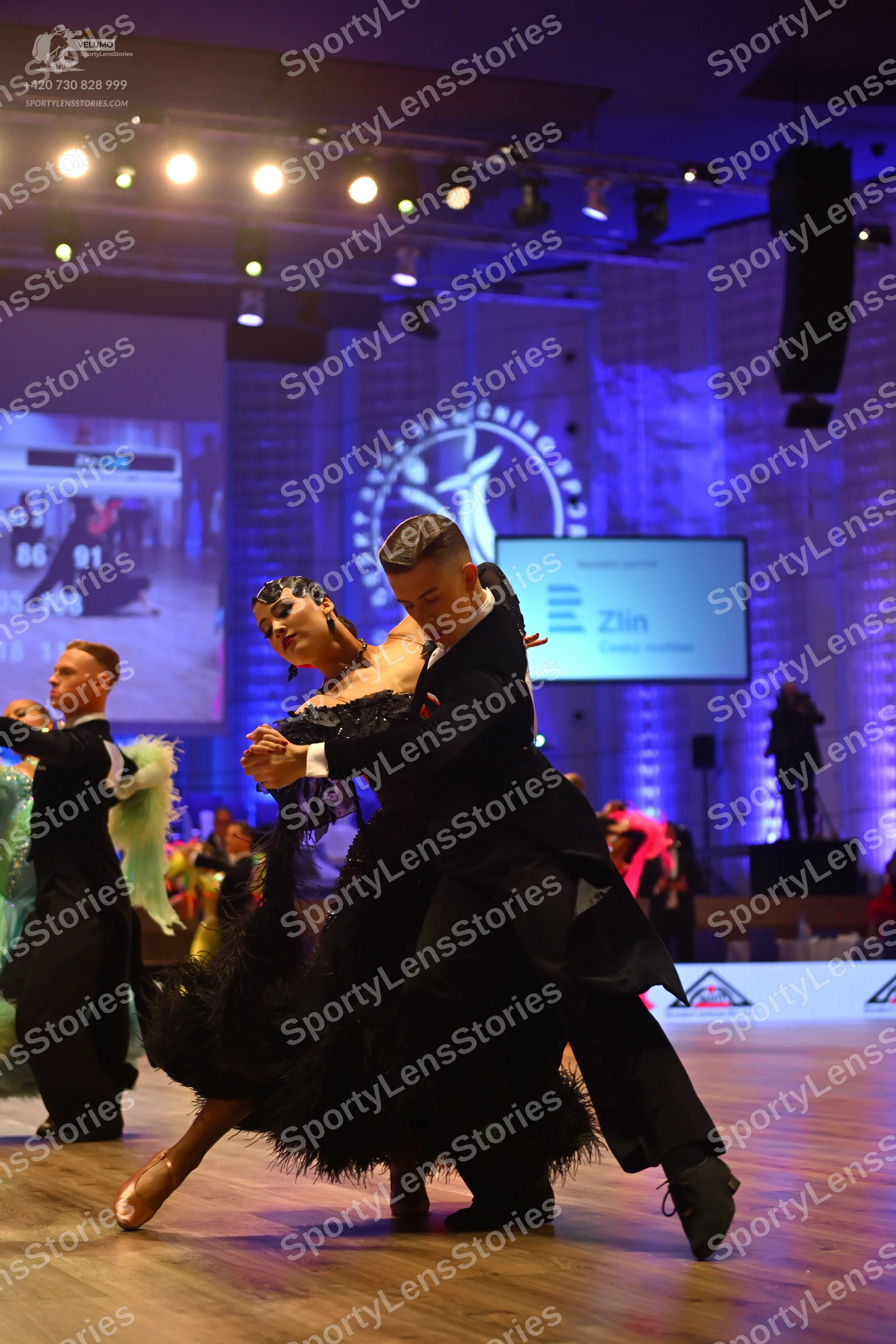 Dancesport competitor: Male dancer (foreground): black suit and black dance shoes