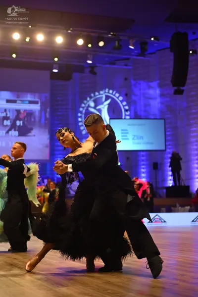 Dancesport competitor: Male dancer (foreground): black suit and black dance shoes