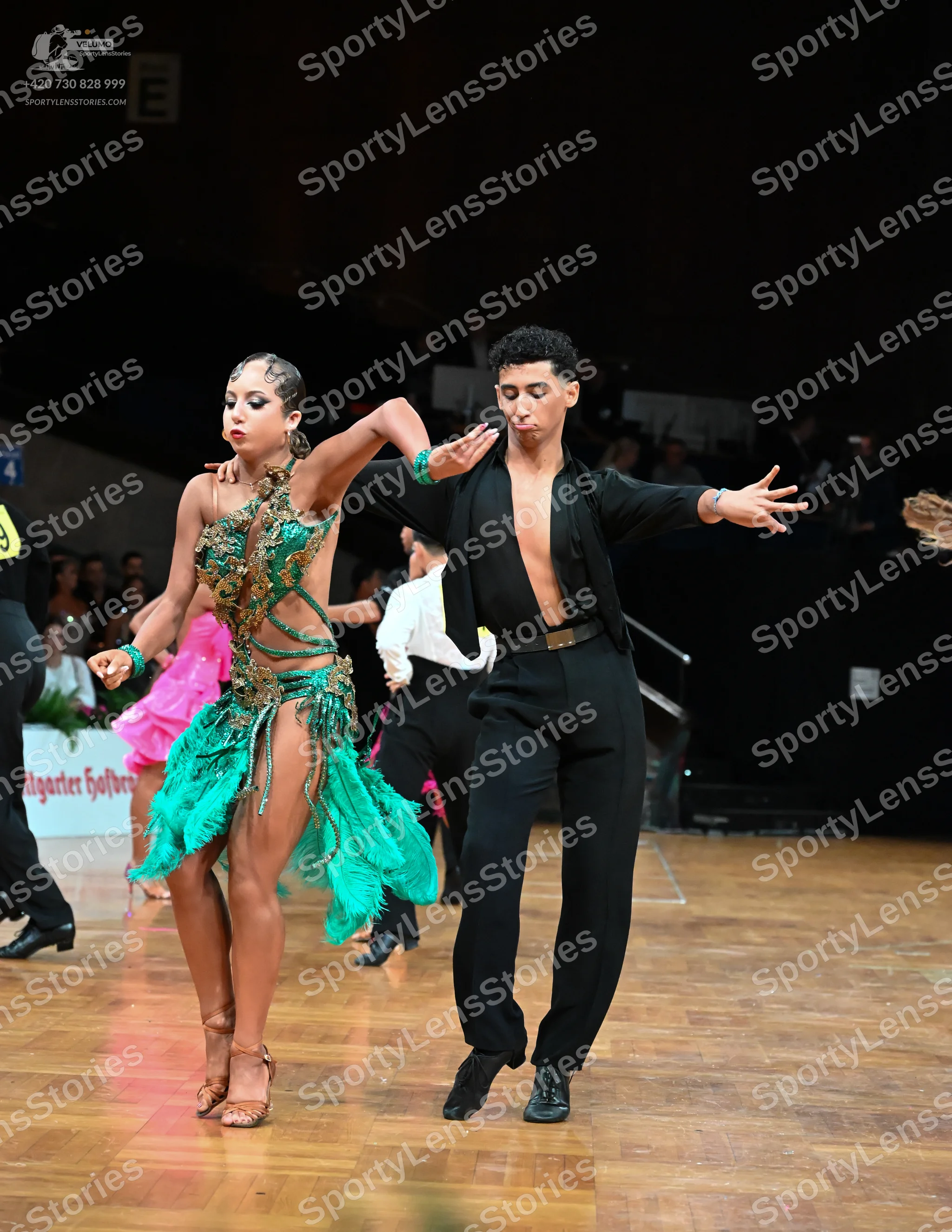 Dancesport competitor: Female dancer: green Latin dance dress with a gold sequined bodice and long gree