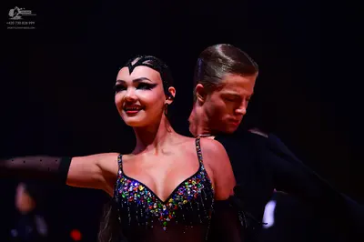 Dancesport competitor: Female dancer: black Latin dance costume with multi-colored sequins and rhinesto