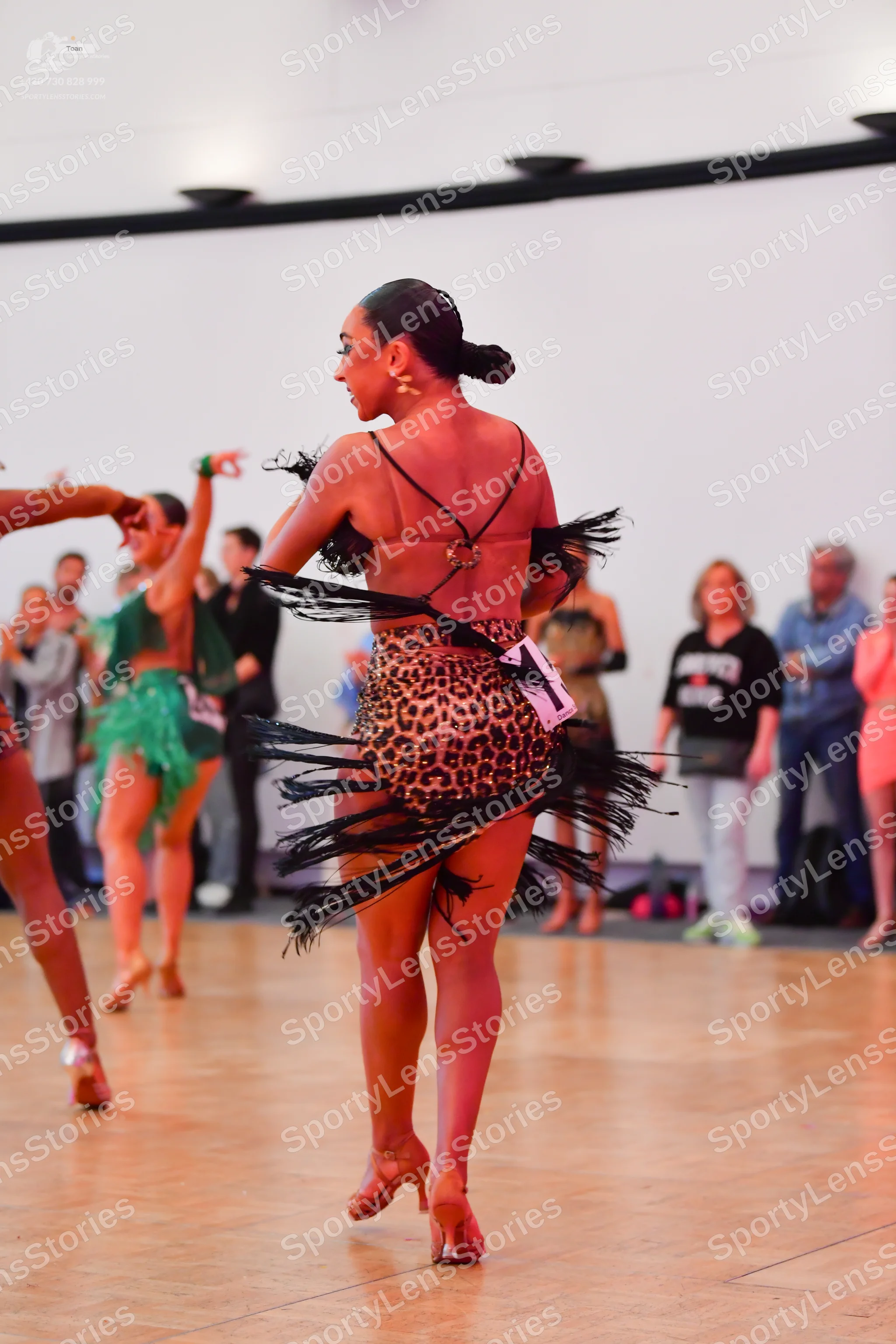 Dancesport competitor: Central female dancer: leopard print Latin dress with black fringe and thin blac