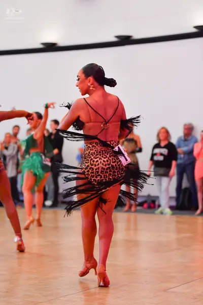 Dancesport competitor: Central female dancer: leopard print Latin dress with black fringe and thin blac
