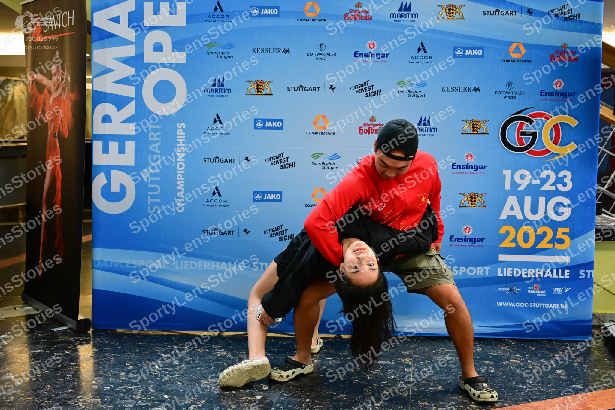 Dancesport competitor: Male dancer: red long-sleeved shirt, khaki shorts, black baseball cap, and black