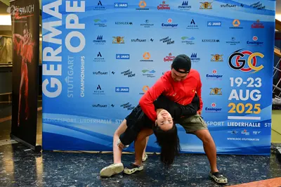 Dancesport competitor: Male dancer: red long-sleeved shirt, khaki shorts, black baseball cap, and black