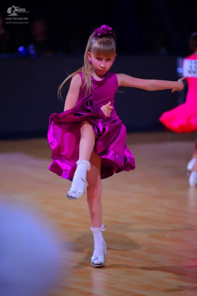 Dancesport competitor: Female dancer: magenta satin ballgown with a full, ruffled skirt and matching fl