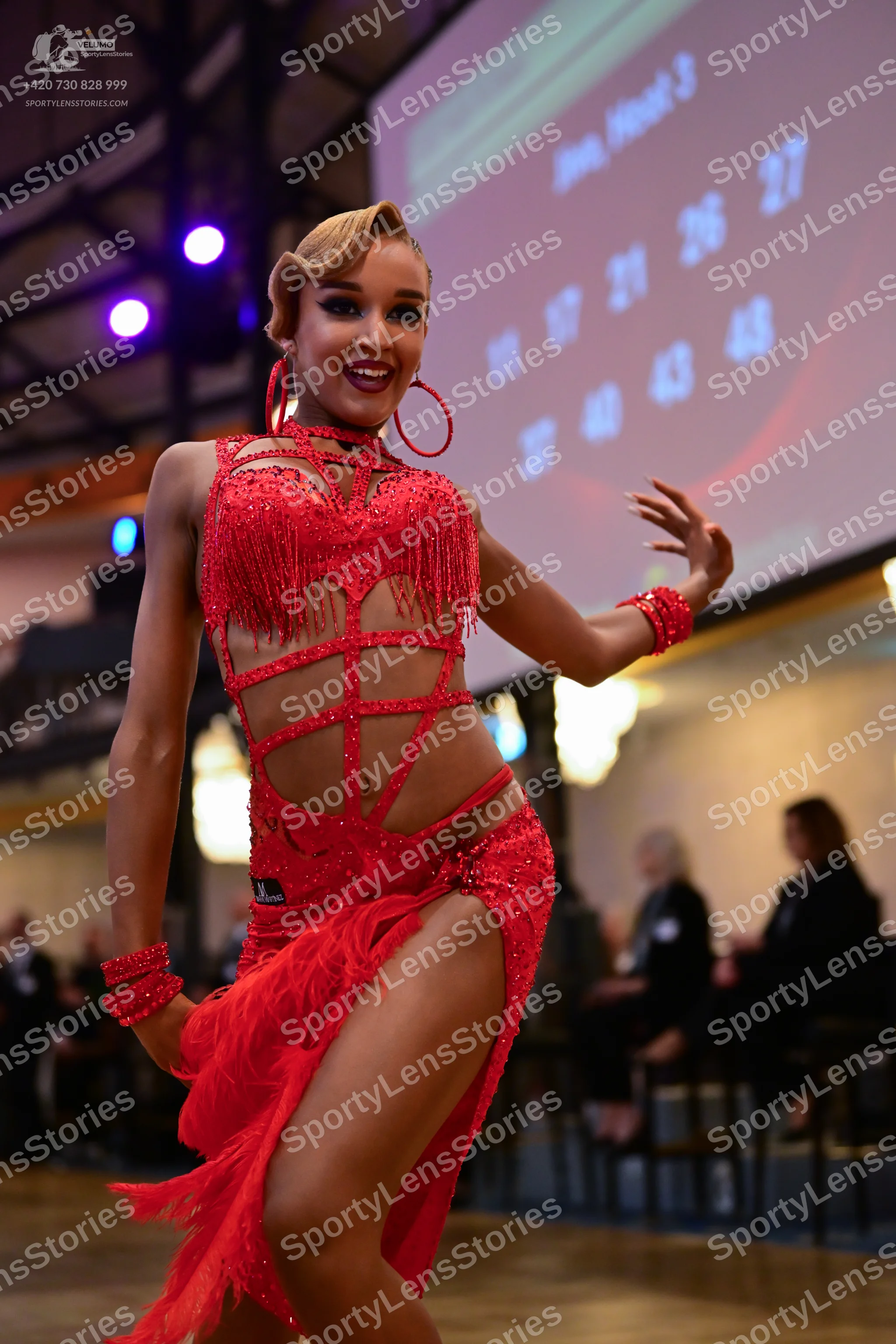 Dancesport competitor: Female dancer: red latin dress with sequins, fringe, and cutout straps, paired w
