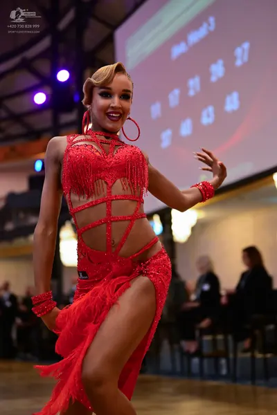 Dancesport competitor: Female dancer: red latin dress with sequins, fringe, and cutout straps, paired w