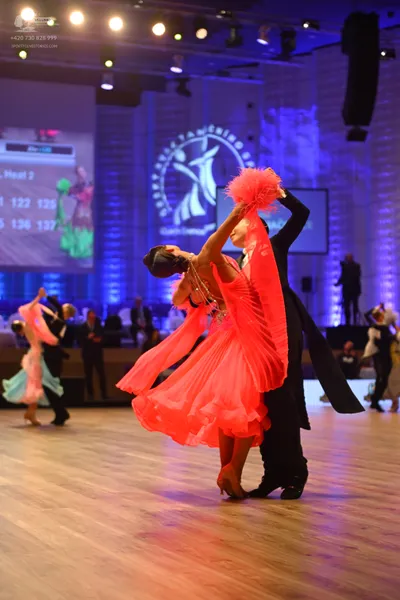Dancesport competitor: Main female dancer: bright red flowing Latin dance dress made of lightweight, la